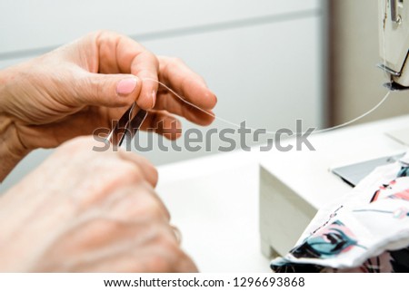 Sewing on a sewing machine. Woman uses a sewing machine to sew clothes, decorations from material. Fashion and beauty concept, sewing clothes. A woman works at home, passion.