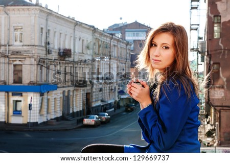girl sitting and drinking tea, blue business suit, the sun shines brightly, looking right, hot tea, wet, cold weather