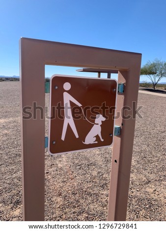 Sign with vector of person walking a dog on a leash in the desert