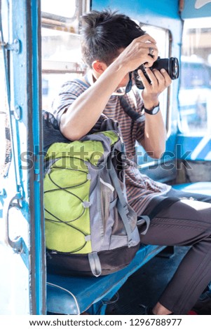 Young asian backpack traveler sit in old bus and take photography. Old local bus in Thailand. Trip to Thailand. Backpack travel concept.