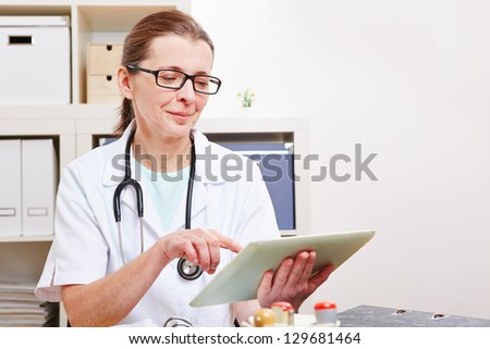Senior female doctor using a tablet computer in her office