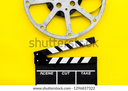 Filmings concept. Clapperboard and film stock on yellow background top view space for text