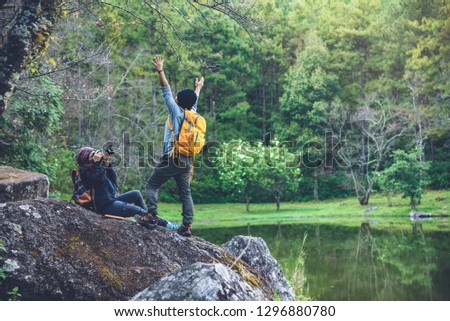 Couple sitting on rocks and taking pictures nature, flowers. 