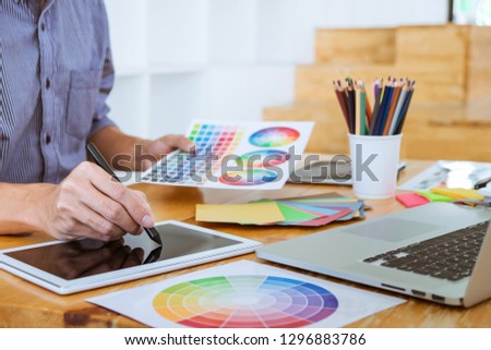 Young creative graphic designer working on project architectural drawing and color swatches, selection coloring on graphic chart with work tools and equipment.