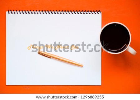 Orange office desk with a notebook - note paper - next to a coffee cup and a golden colored pencil, in a work environment - office and natural light - Phrases