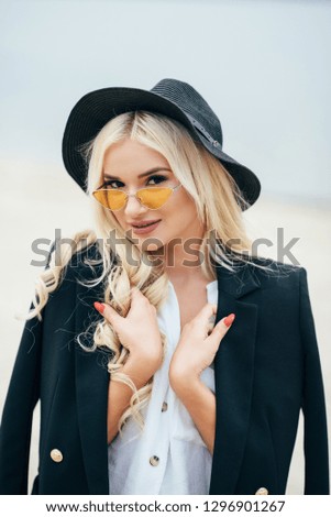 Cute blonde girl in glasses walks along the coast and enjoy life