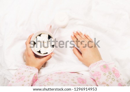 Women's hands with coffee and meringue in bed.Top view.