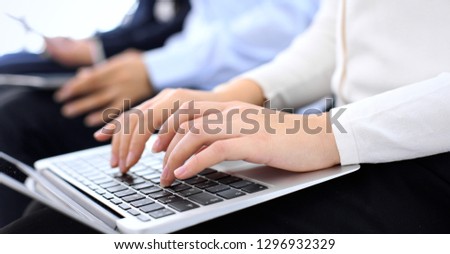 Group of business people sitting in office waiting for job interview, close-up. Hands of woman working on laptop. Conference or training concepts