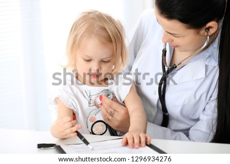 Doctor and patient baby in hospital. Little girl is being examined by pediatrician with stethoscope. Health care, insurance and help concept