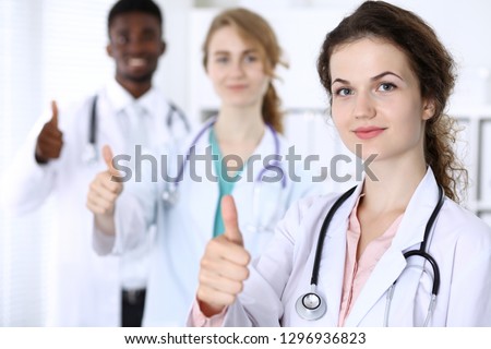 Happy doctor woman showing Ok sign with medical staff at the hospital. Multi ethnic people group