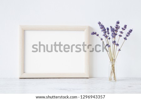 Dried purple lavender in vase on shelf at light gray wall. Mockup for positive idea. Empty place for inspirational, emotional, sentimental text, quote, sayings or photo in white frame. Front view.