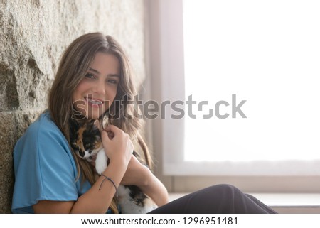 Close up of female owner holding her lovely black and white cat at home. Concept of love to animals, pets, care, tranquility.