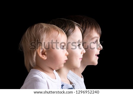 Family portrait of three boys, profile picture of them all in a row, isolated on black background, color version