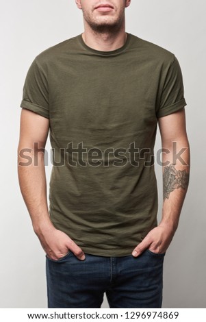 partial view of tattooed man in khaki t-shirt with copy space isolated on grey Royalty-Free Stock Photo #1296974869