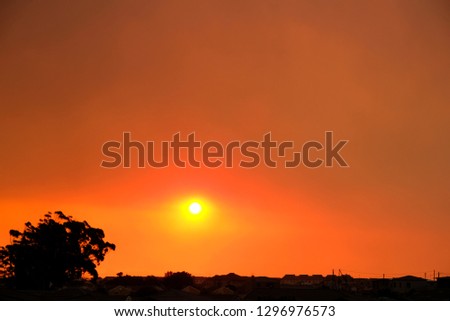 Sunset while fire burns smoke-filled sky
