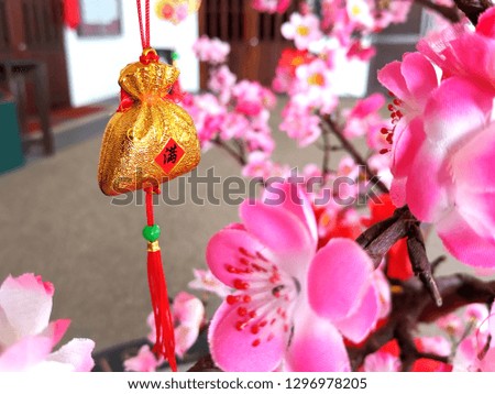 Chinese New Year decorations hanging on the sakura tree. Close up image, selective focus, shallow DOF. Chinese character means that happy chinese new year.