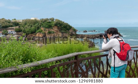 mature woman photographer taking a picture at seaside