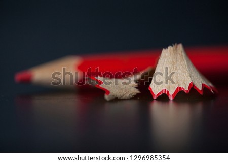 Red pencil and shavings on black background. Selective focus.