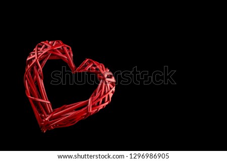 Valentine's day. Isolated. Red Heart with a hole woven from a vine. On black background.