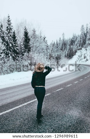 young girl in a hat and a plaid shirt is on the road
winter forest road
travel of women in beautiful nature