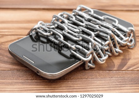 Smartphone wrapped by chain on the wooden table. 