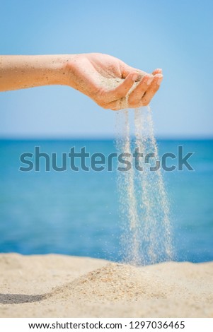 hands are pouring sand by the sea