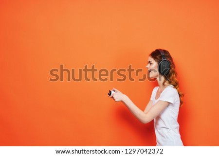woman in headphones playing console over orange background
