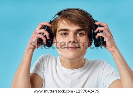 Cheerful guy listening to music with headphones on a blue background