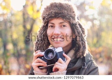 Young woman taking pictures in the autumn park. Concept girl photographer. Soft focus
