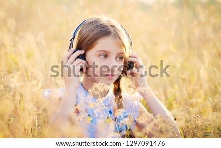 Teenage girl listening to music with headphones in sunshine field