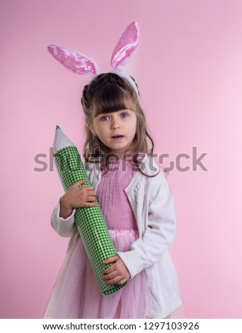 Cute kid dressed as the Easter bunny standing on pink background and celebrating. Child Easter Holiday Concept. 