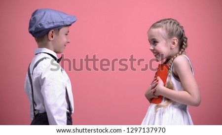 Male kid in formal wear presenting birthday gift card to happy surprised lady