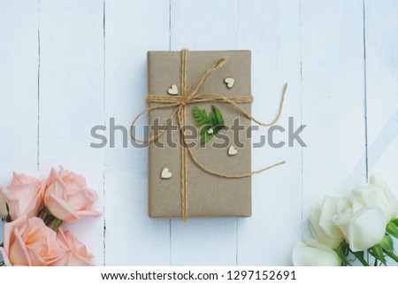Brown eco friendly gift box decorated with soft pink and white rose on white wooden table, sweet lovely present valentine concept, copy space