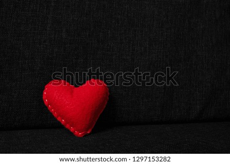 Red valentines day heart made from wool on dark fabric background. Concept of love 
