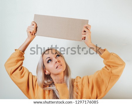 The girl looks at the empty poster in his hands over his head.