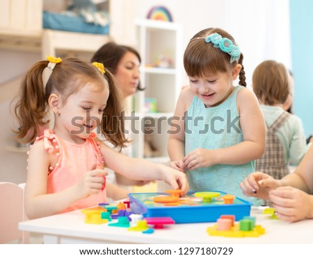Happy children playing with plastic building blocks at kindergarten