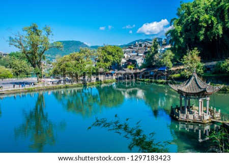 The traditional Chinese arbor in the middle of beautiful pond in Heshun village. Tengchong area, Yunnan province, China. Translation is "The heart of the Green Dragon pond".