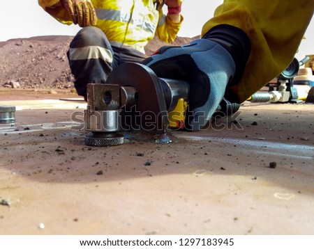 Picture of industrial constructer worker hand wearing a glove inserting pull tester unit into welding lug on the steel test plate construction site Sydney, Australia 