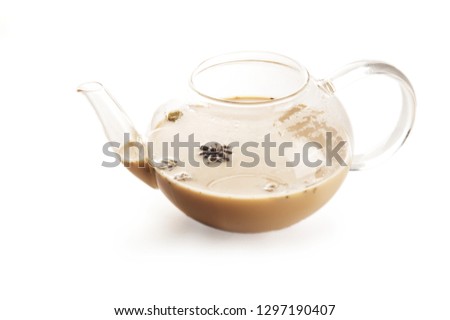 Teapot transparent teapot with indian national masala tea isolated on white background. Milk, ginger, cardamom, cloves, nutmeg, star anise, cinnamon