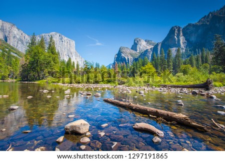 Classic view of scenic Yosemite Valley with famous El Capitan rock climbing summit and idyllic Merced river on a sunny day with blue sky and clouds in summer, Yosemite National Park, California, USA Royalty-Free Stock Photo #1297191865