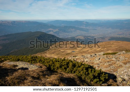 Panoramic view of idyllic mountain scenery in the Carpathians Mountains with fresh green meadows in a beautiful sunny day in autumntime. Lake in mountains