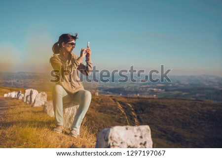 Woman taking  a picture with a cellphone to the beautiful landscape
