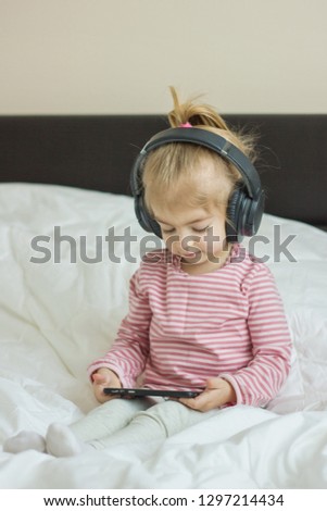 Cute little girl enjoying listening the music with her headphones.