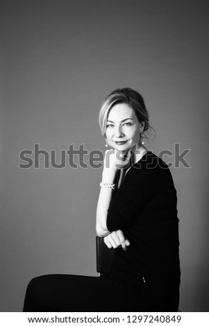 Portrait of beautiful woman in a black dress against grey background