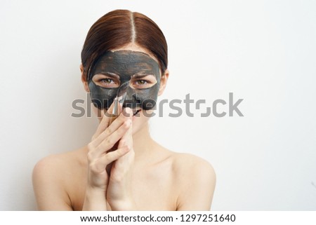 woman in a cosmetic mask made of clay in hand makeup brush