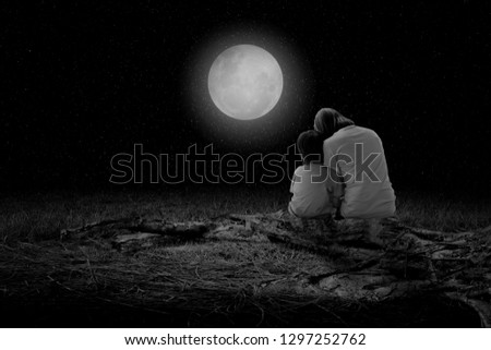 Mother and boy sat to watch the moon on the full moon night.(black and white picture)