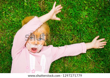 little girl with painted face having fun on grass
