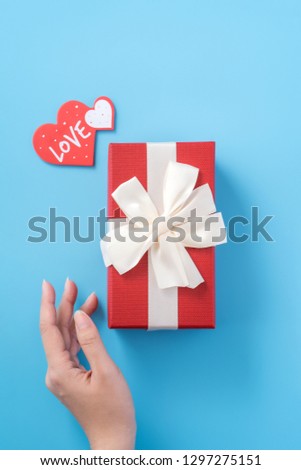 A young woman is giving a gift with greeting on blue background, concept of holiday and celebrate for festival surprising, copyspace, topview