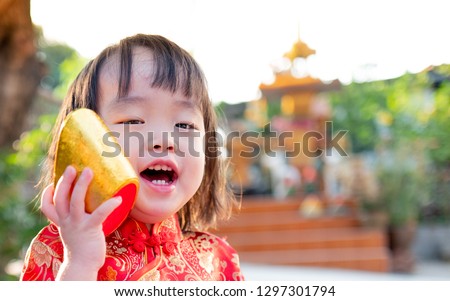 Asian children in Chinese costumes hold gold, laugh happily.