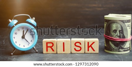 Money, clock and wooden blocks with the word Risk. The concept of financial risk. Justified risks. Investing in a business project. Making the right decision. Property insurance. Legal / market risks